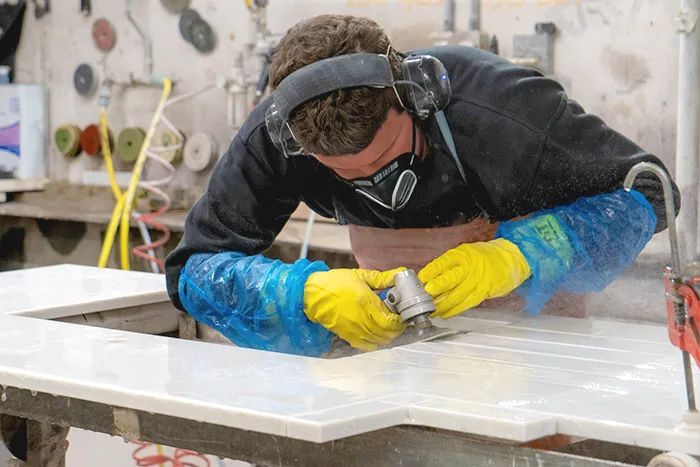 Close-up of Costa's Stone fabricators meticulously matching veining for a complex quartz waterfall island installation in MA.